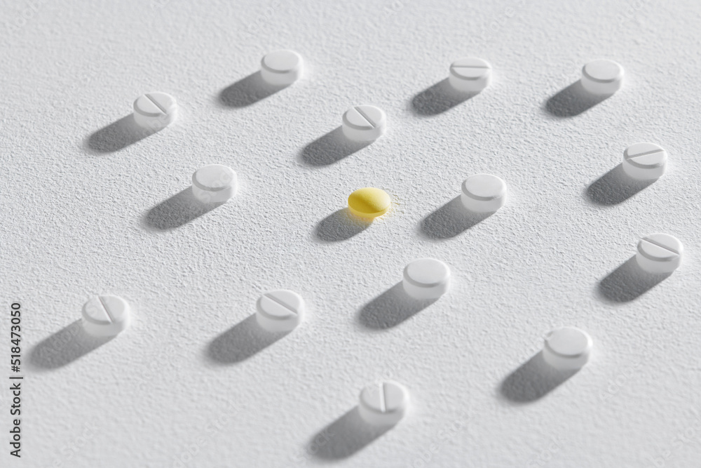 Yellow pill among white ones on white background with shadow Yellow pill among white ones on white background with shadow