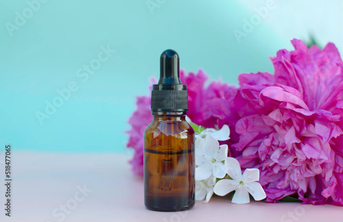 Pink peony and brown glass dropper bottle with serum  essential oil or other cosmetic product and orange flowers on a yellow background. The concept of natural cosmetics for skin care