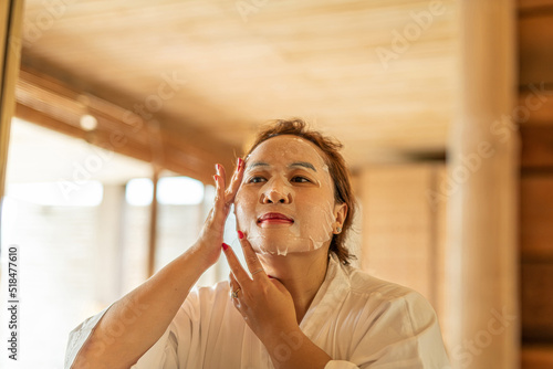 Beautiful young woman uses sheet moisturizing face mask photo