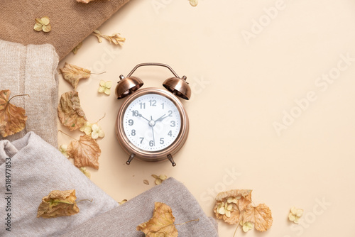 larm clock and cozy sweaters with copy space on beige background. Top view photo
