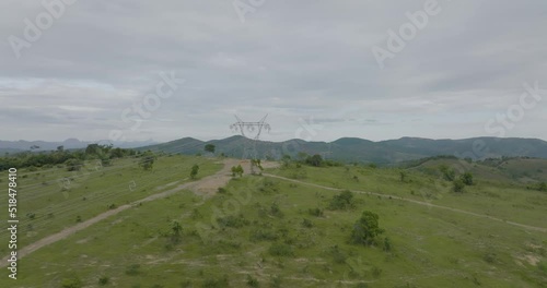Aerial flying forward over overhead powerlines in countryside on cloudy day photo
