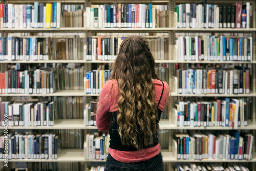 Student Looking At Bookshelves In Library photo