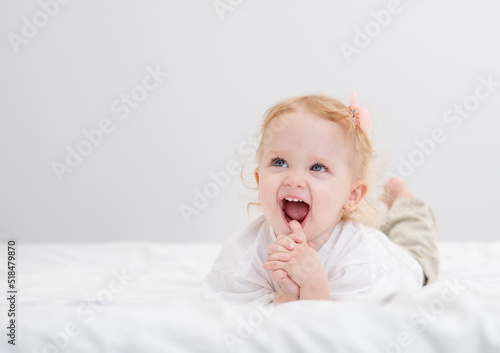 Little girl lying on the bed in the bedroom and with a cute smile