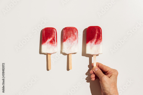 Hand holding homemade strawberry ice cream pops