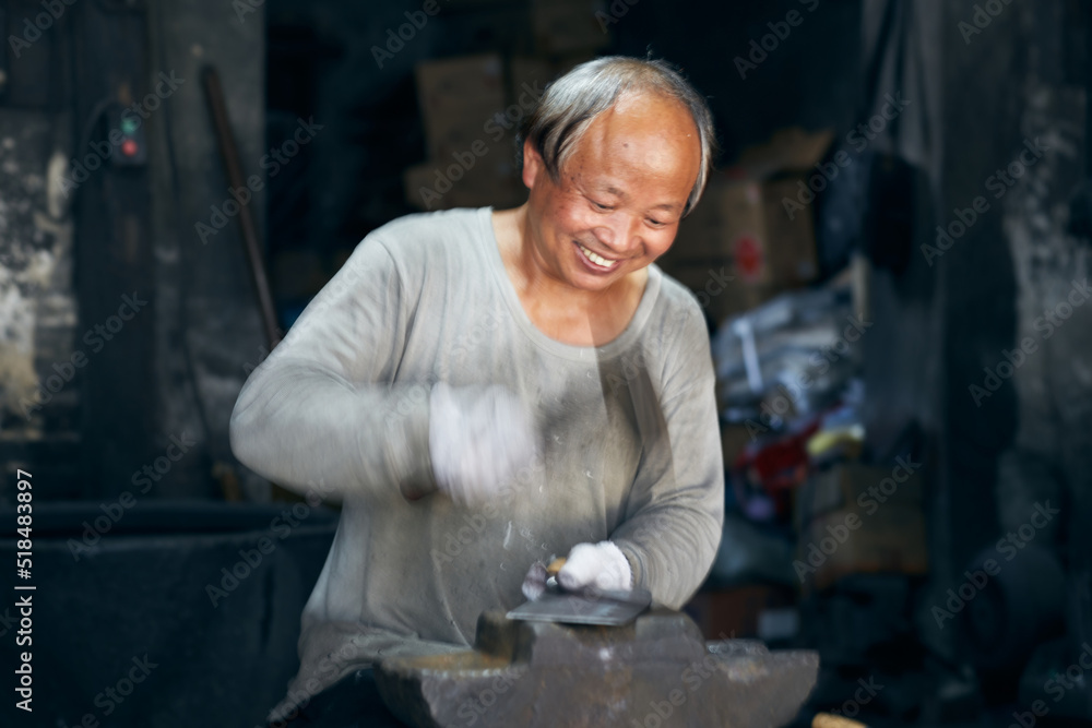 An East Asian Ironworker manufactures a Chinese kitchen knife. An East Asian Ironworker manufactures a Chinese kitchen knife.