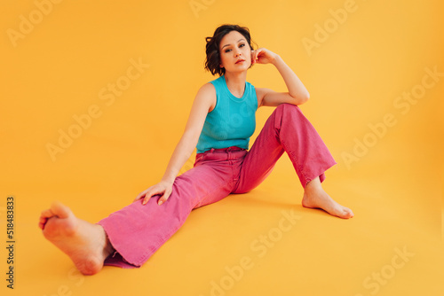 Stylish barefoot woman sitting in studio photo