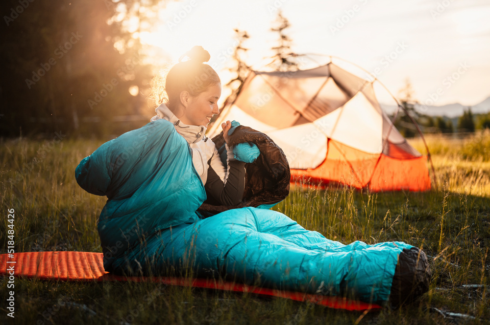 Woman relaxing and lie in a sleeping bag in the tent. Sunset camping in