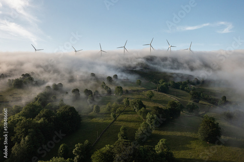 foggy pastures with windmills above the clouds