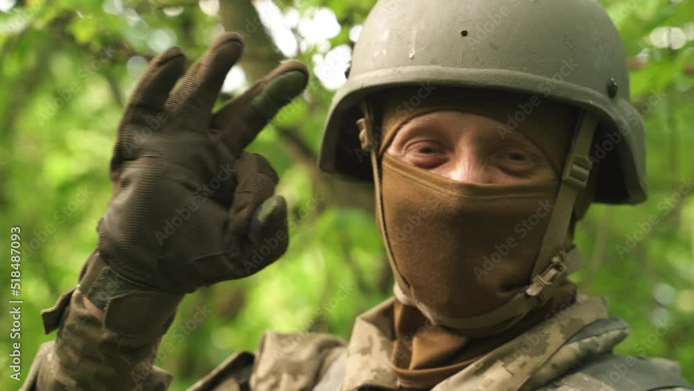 the soldier smiles and shows the OK sign with his fingers. a successfully completed military task. a soldier's full protective gear. Ukrainian military man with a with a good mood. victory in the war the soldier smiles and shows the OK sign with his fingers. a successfully completed military task. a soldier's full protective gear. Ukrainian military man with a with a good mood. victory in the war