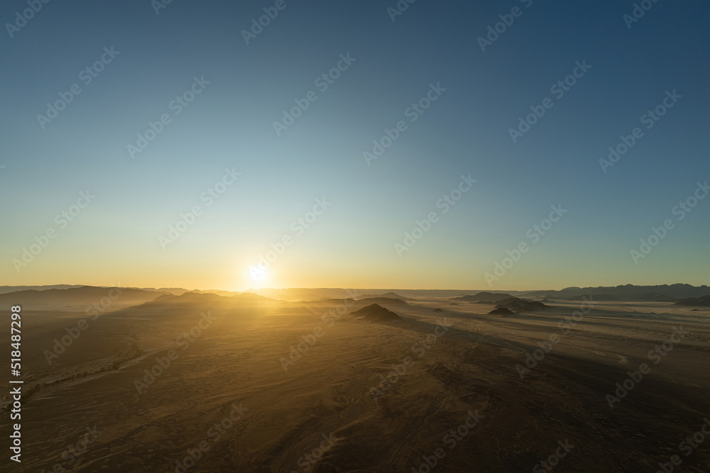 Sunrise seen from a hot air balloon during a ride in Sossusvlei, Namibia. sunbeams shine over the hills and mountains of the Namib-Desert.
