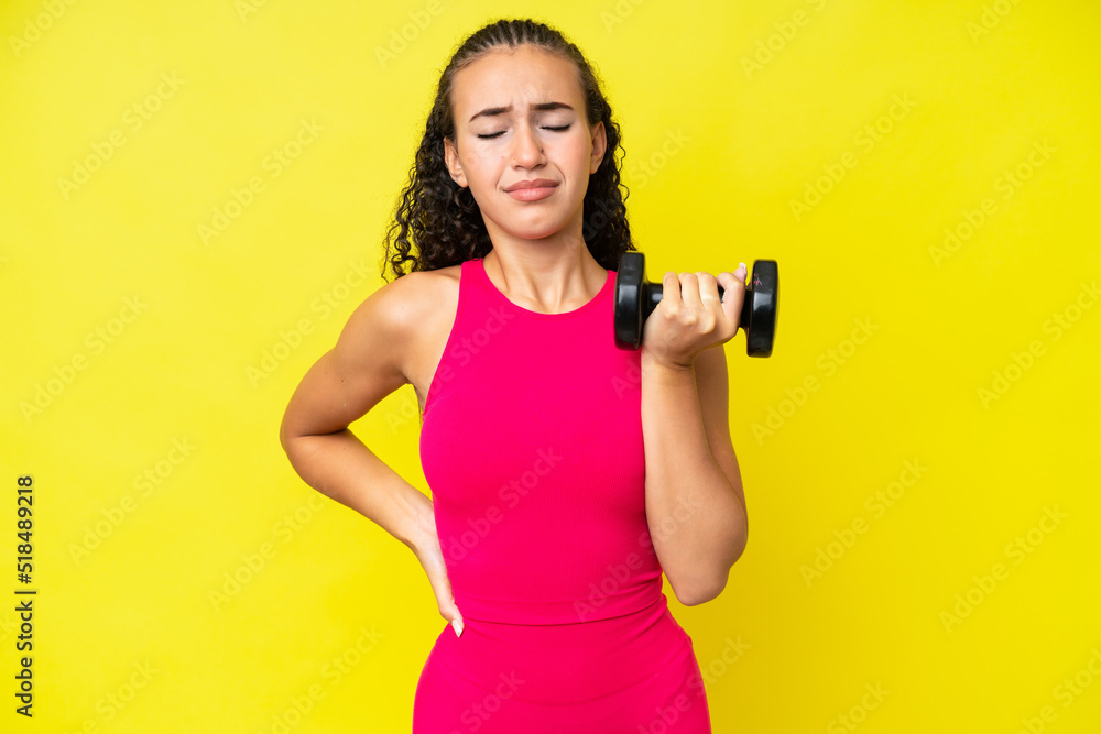 Young sport woman making weightlifting isolated on yellow background suffering from backache for having made an effort Young sport woman making weightlifting isolated on yellow background suffering from backache for having made an effort