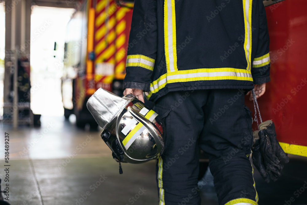 Firefighter in the fire house next to the fire truck Firefighter in the fire house next to the fire truck