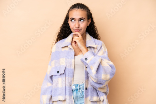 Young woman isolated on beige background thinking an idea while looking up