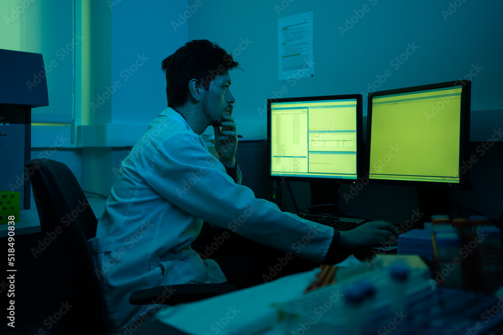 Scientist Working In A Blueish Laboratory Next To The Computer. Scientist Working In A Blueish Laboratory Next To The Computer.