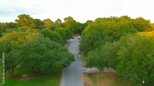 Flying between trees in a rural Texas neighborhood | Aerial fly by shot | Evening time lighting photo