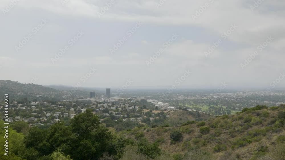 Static shot of white clouds rolling over city surrounded by hills covered with green vegetation at daytime. Cityscape. Static shot of white clouds rolling over city surrounded by hills covered with green vegetation at daytime. Cityscape.