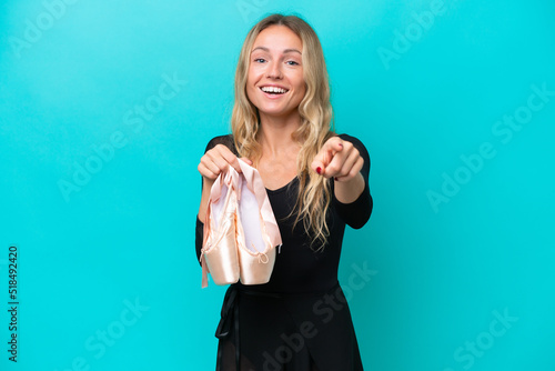 Young Russian woman practicing ballet isolated on blue background surprised and pointing front