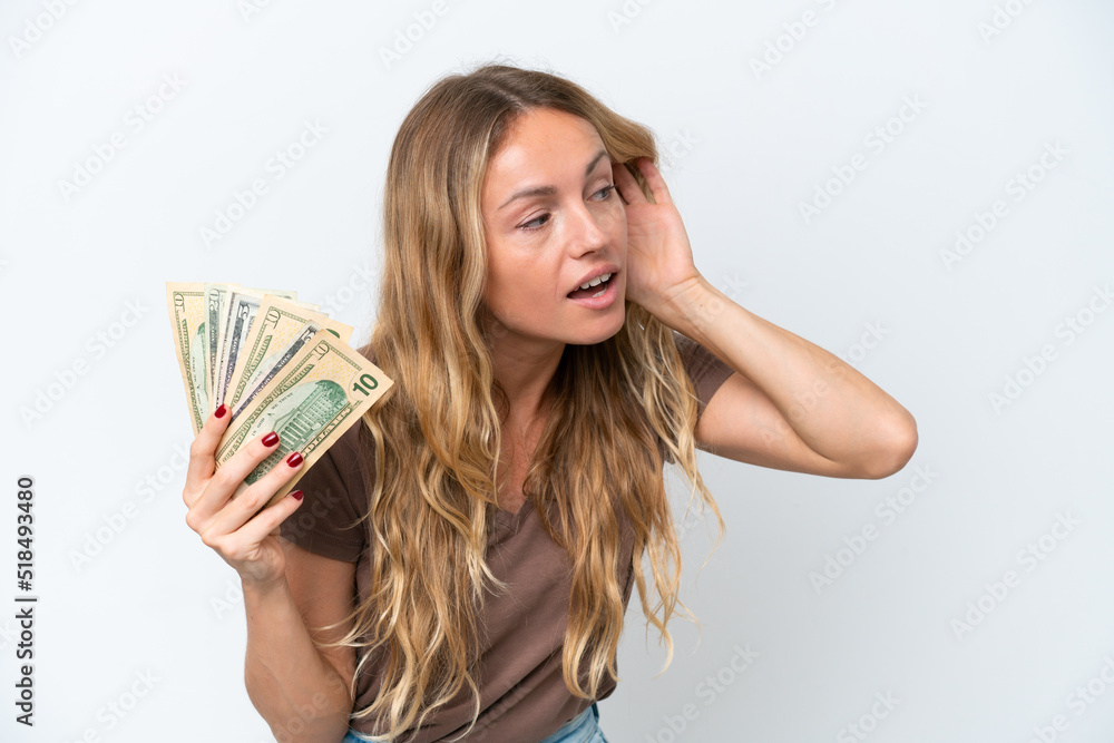 Young Russian woman taking a lot of money isolated on white background listening to something by putting hand on the ear Young Russian woman taking a lot of money isolated on white background listening to something by putting hand on the ear