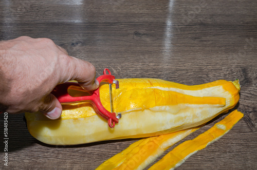 The cook peels the zucchini with a knife on the kitchen table	
 photo