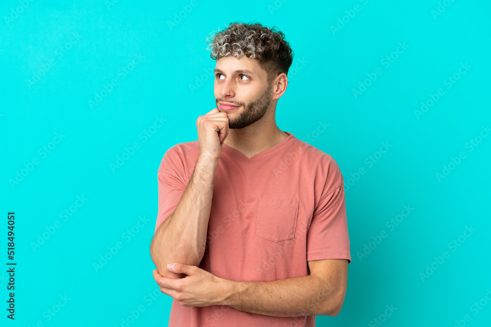 Young handsome caucasian man isolated on blue background and looking up Young handsome caucasian man isolated on blue background and looking up