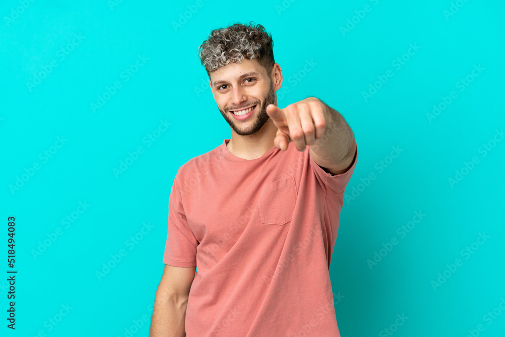 Young handsome caucasian man isolated on blue background pointing front with happy expression Young handsome caucasian man isolated on blue background pointing front with happy expression