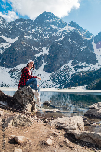 A woman is sitting on the shore of a lake. Morskie Oko, Tatras mountains.