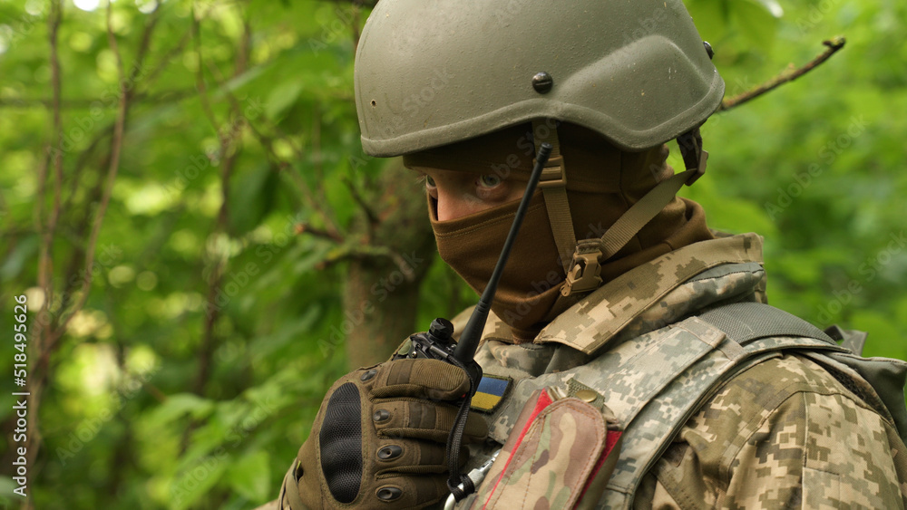 a portrait of a Ukrainian military man communicating by radio. a military  man in the forest reports news on a walkie-talkie and gives orders.  communication between units during a combat mission Stock-foto