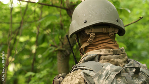 a portrait of a Ukrainian military man communicating by radio. a military man in the forest reports news on a walkie-talkie and gives orders. communication between units during a combat mission photo