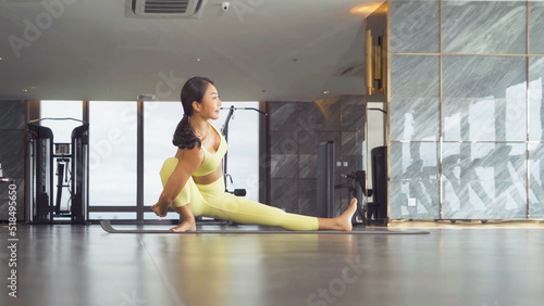 An Asian woman in yoga class club doing exercise and yoga at fitness center or gym. Indoor in sport and recreation concept. People lifestyle activity with urban city view.