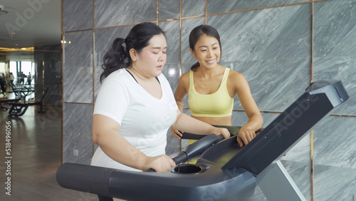 Fat Asian healthy woman, person, running or jogging on treadmill for diet, and training in gym or fitness center in sport and recreation concept. Lifestyle activity. Losing weight with a trainer coach