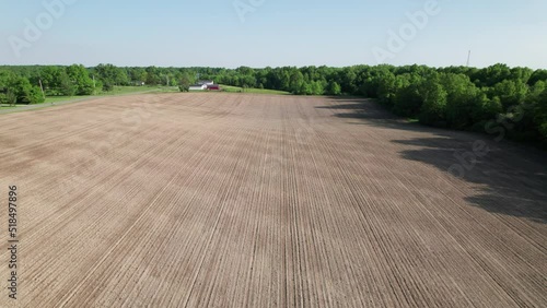 Aerial view of farm house and farm field with rows of plants under brght blue sky photo