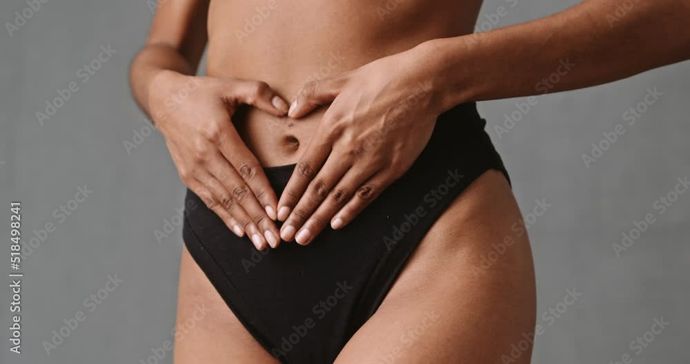 Close up woman hands making heart shape on stomach Close up woman hands making heart shape on stomach