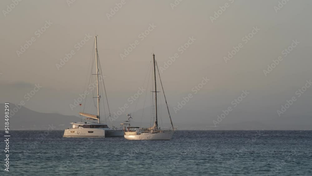 Sailboats anchored in Canary sway from side to side in sunset glow; static Sailboats anchored in Canary sway from side to side in sunset glow; static
