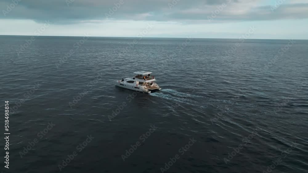 Tourists In Catamaran Yacht Sailing During Sunset Near Funchal Bay In Madeira Island, Portugal. Aerial Orbiting Shot Tourists In Catamaran Yacht Sailing During Sunset Near Funchal Bay In Madeira Island, Portugal. Aerial Orbiting Shot