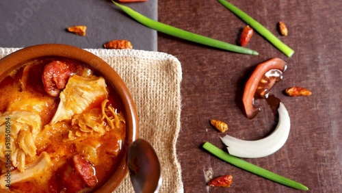 Typical Spanish food tapa callos,  with chorizo ​​and several of its ingredients on the side on a wooden and slate background