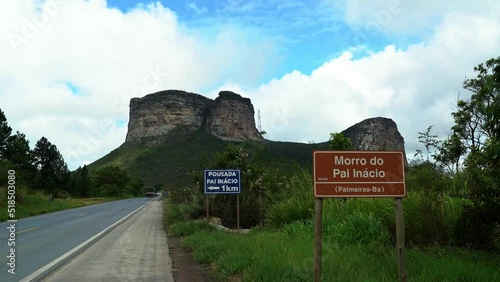 Tilting down landscape shot of the famous Mount of Pai Inácio in the Chapada Diamantina national park in northern Brazil on a warm sunny summer day from the highway with semi trucks passing by. photo