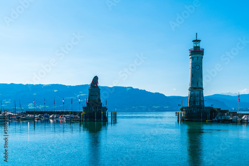 Germany, Lindau island city harbor lighthouse with view to austria and bregenz city early in the morning with blue sky and sun in summer