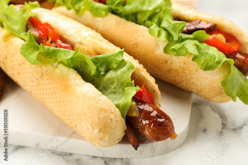 Tasty hot dogs on white marble table, closeup. Fast food