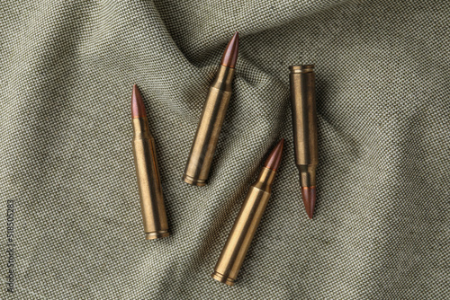 Many brass bullets on burlap, flat lay