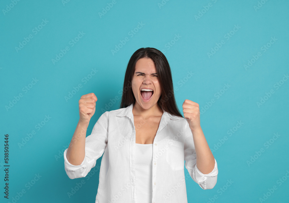 Aggressive young woman shouting on turquoise background Aggressive young woman shouting on turquoise background