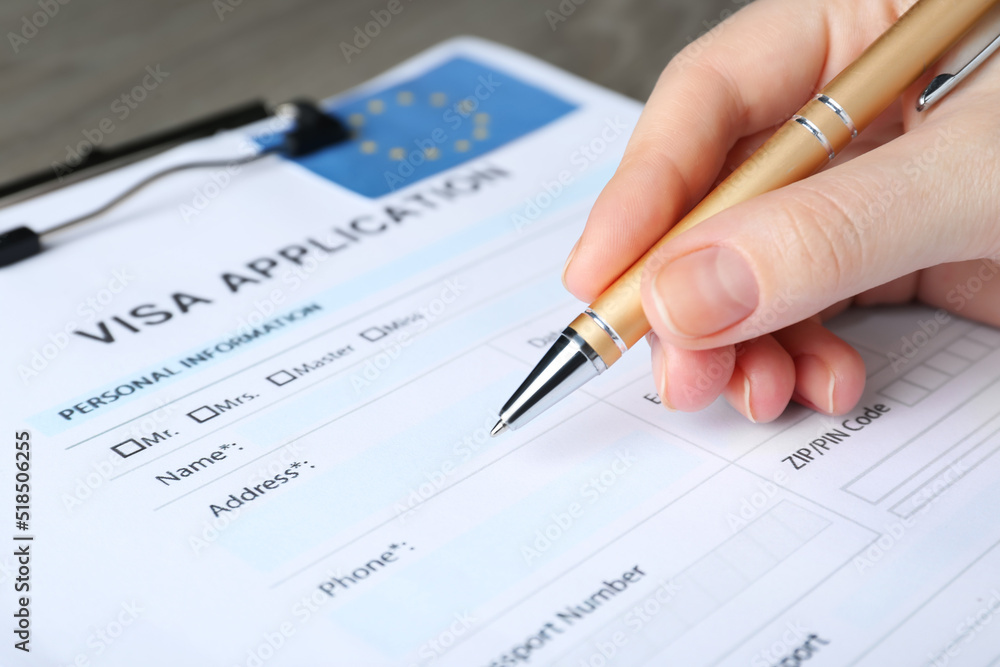 Woman filling visa application form for immigration to European Union at table, closeup Woman filling visa application form for immigration to European Union at table, closeup