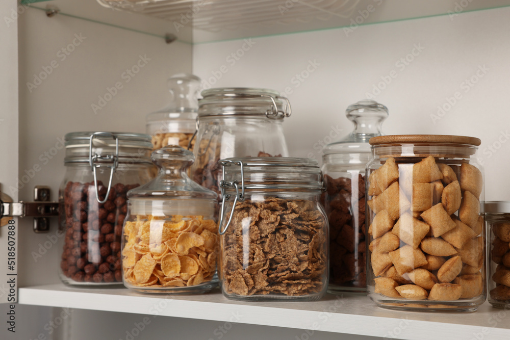 Glass containers with different breakfast cereals on shelf Glass containers with different breakfast cereals on shelf