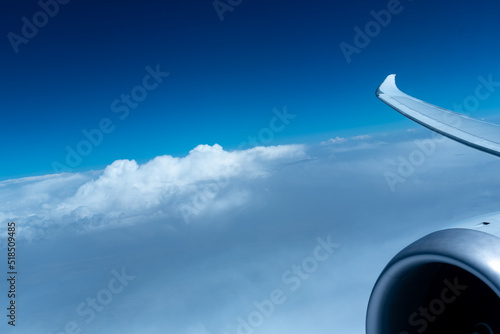 View of the engine and wing of airplane between the clouds from the window in flight.