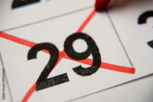 The 29st number in the calendar is crossed out with a red cross in a macro on a white sheet. Calendar for plans, notes, meetings. Business calendar. Marker for notes in the calendar photo