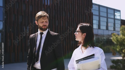 Wallpaper Mural Handsome Caucasian male boss in suit and tie walking the street together with beautiful female assistant with documents and talking about work. Man employer and woman employee discussing job. Torontodigital.ca