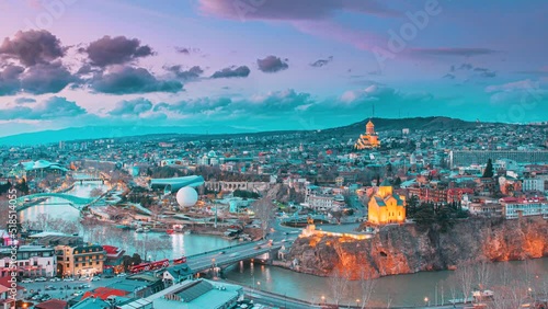 Tbilisi, Georgia. day to night time lapse timelapse. Top View Of Famous Landmarks In spring sunset Evening dusk night. Georgian Capital Skyline Cityscape. Justice House, Bridge Of Peace, Concert Hall photo