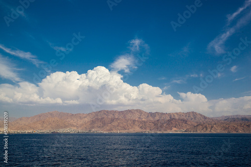 Nice view of the sea and mountains. Massive white clouds hung over the mountain range on the seashore. View of the Jordanian Gulf. A beautiful place for tourism with a gorgeous view. 