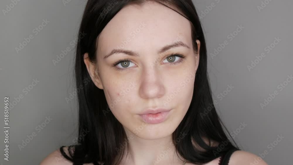 Beautiful girl model posing in front of the camera. Young woman without makeup before applying makeup on gray background Beautiful girl model posing in front of the camera. Young woman without makeup before applying makeup on gray background