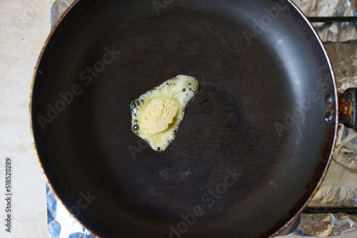 butter pat melting on a black cast iron frying pan. photo