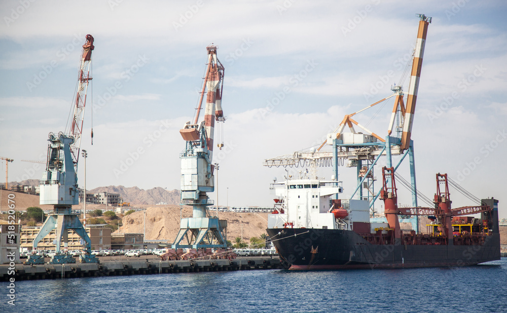 Large loading cranes in the international port of Israel. A ship is moored near the cranes, waiting for the goods to be loaded on board. International logistics and trade. 